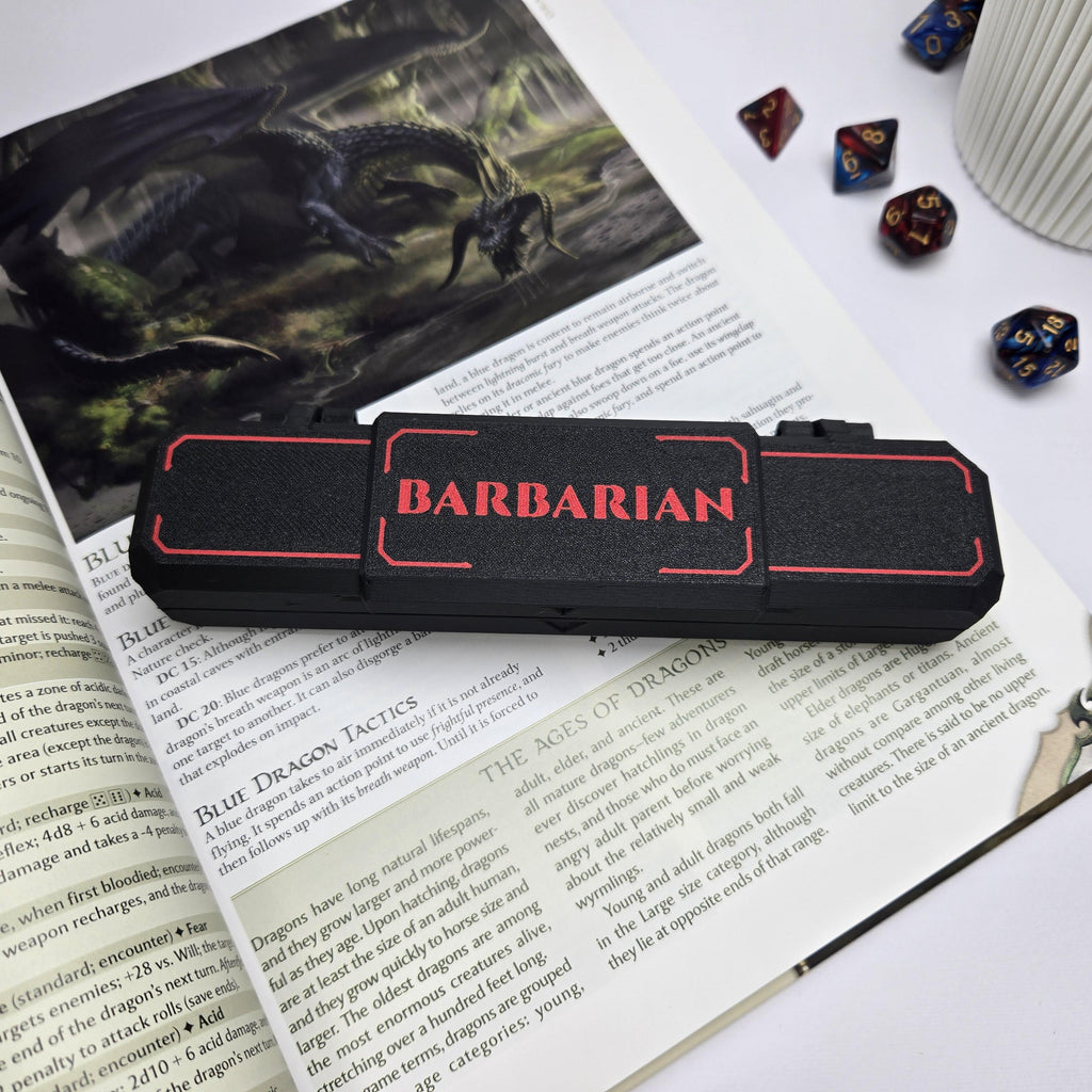 Black and red 'Barbarian' case on top of a book with game-related items around